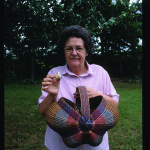 Basketmaker Trevle Wood, of Murfreesboro, with two of her original forms—a tiny miniature and a colorful “butterfly basket.”  Photo by Robert Cogswell, 1999.