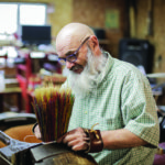 Master artist Jack Martin stitches a rainbow broom at his shop in Selmer, TN.