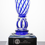 A glass trophy with blue swirls on a black base. The base features an engraved plaque that reads, 2020 Governor’s Arts Award along with a circular logo—part of the distinguished Governor's Arts Awards – Previous Awards collection.