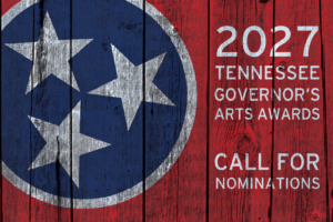 The image shows the Tennessee state flag painted on wooden planks with text announcing the 2027 Tennessee Governor’s Arts Awards Call for Nominations in white letters on a red background.