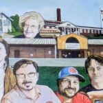 A mural features six people in front of a school building with a United States flag, a bus, and an older womans face above the school. A historic house appears in the upper left corner. The people are smiling and facing forward.