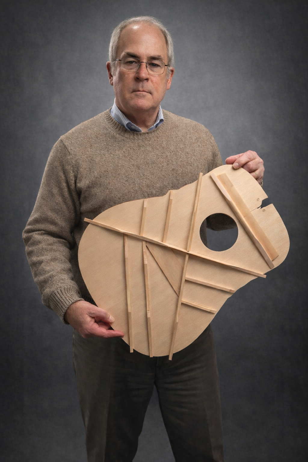 Bruce Scism holding a braced acoustic guitar top